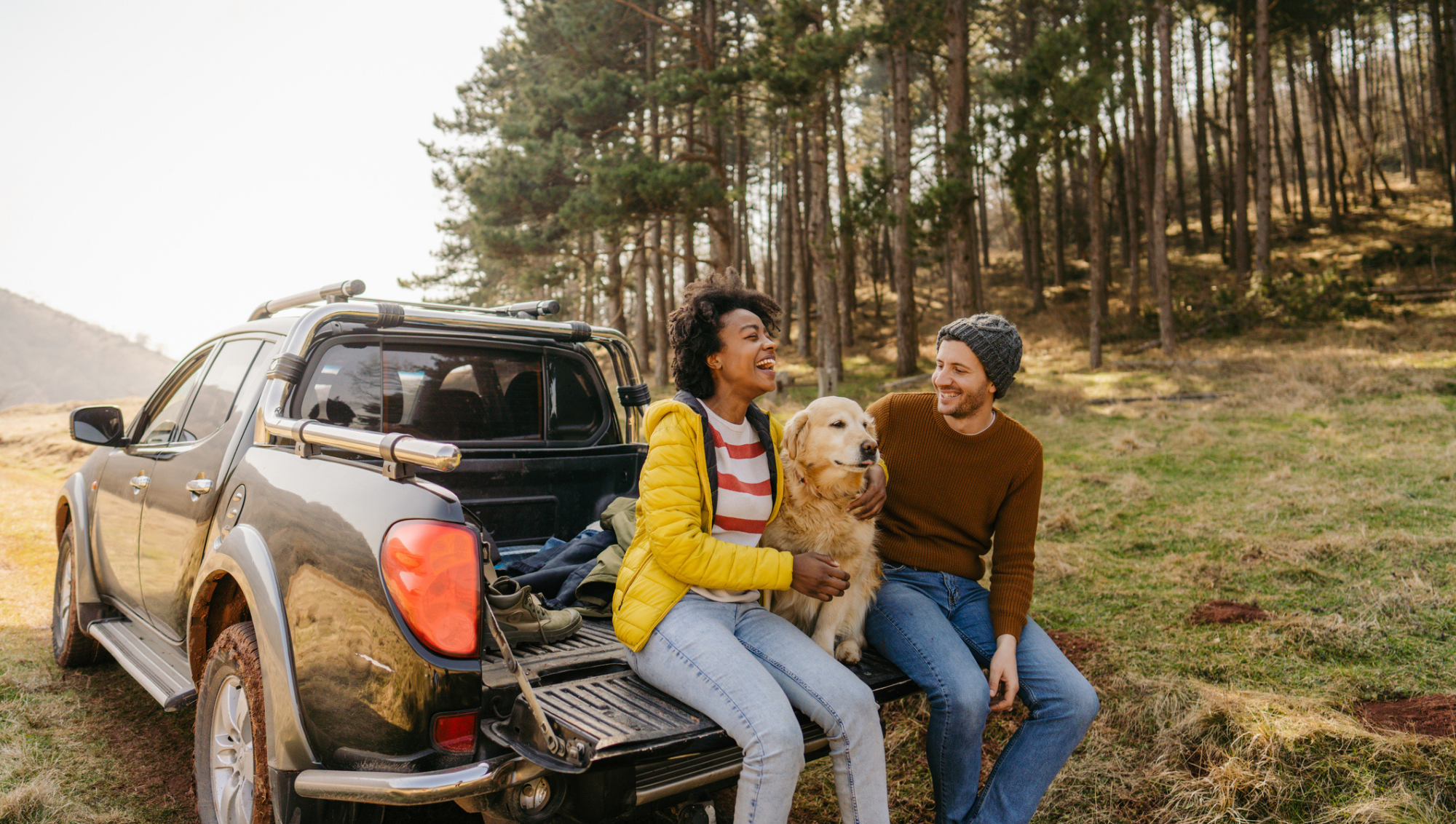 Couple sitting on tailgate of truck with a dog