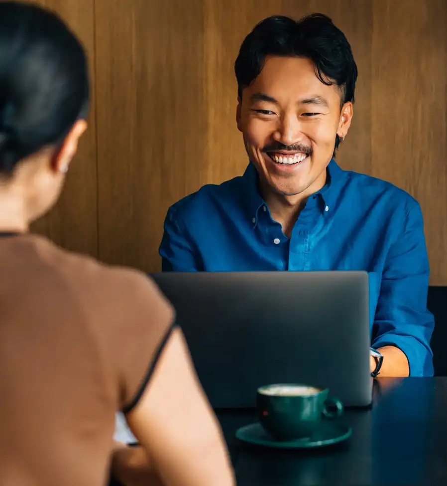 man smiling at woman in cafe with laptop sq crop GettyImages-2170146551 man smiling at woman in cafe with laptop